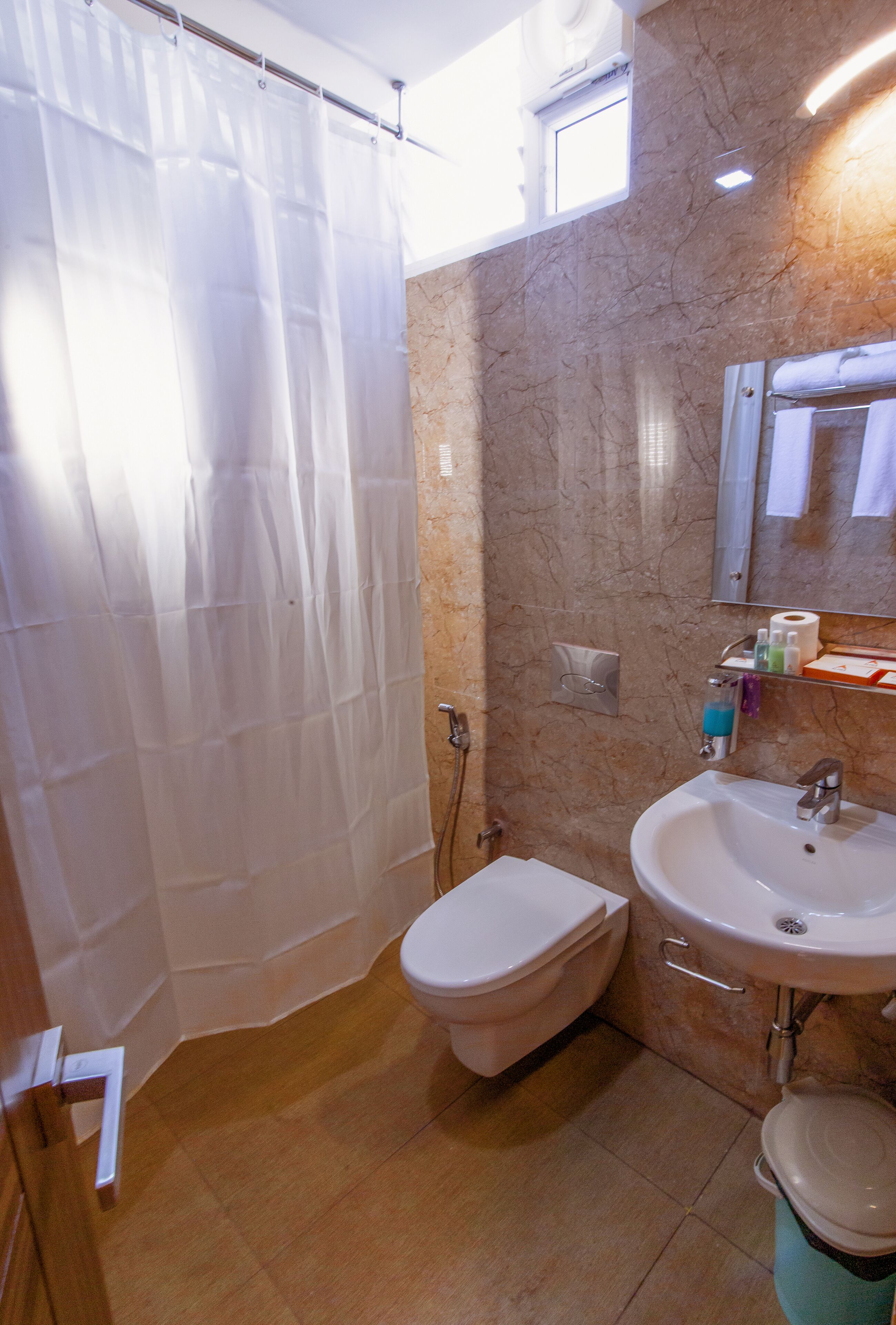A bathroom with a shower curtain, toilet, sink, and marble walls.