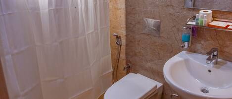 A bathroom with a shower curtain, toilet, sink, and marble walls.