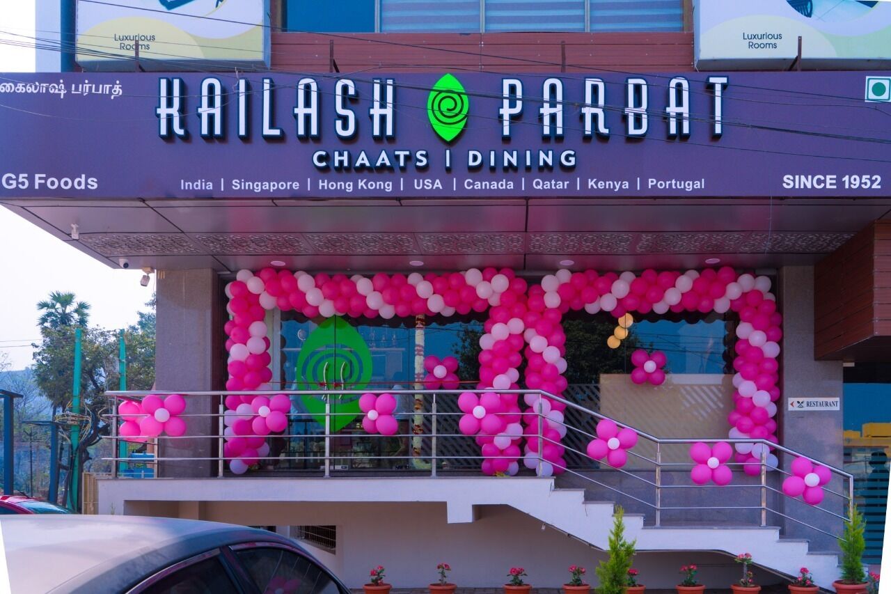 A building with a sign for Kailash Parbat Chaats Dining, listing locations including India, Singapore, Hong Kong, USA, Canada, Qatar, Kenya, and Portugal.