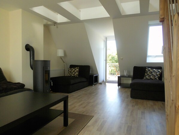 Ein modernes Wohnzimmer mit Kamin, zwei Sofas, einem Couchtisch und Blick ins Freie.