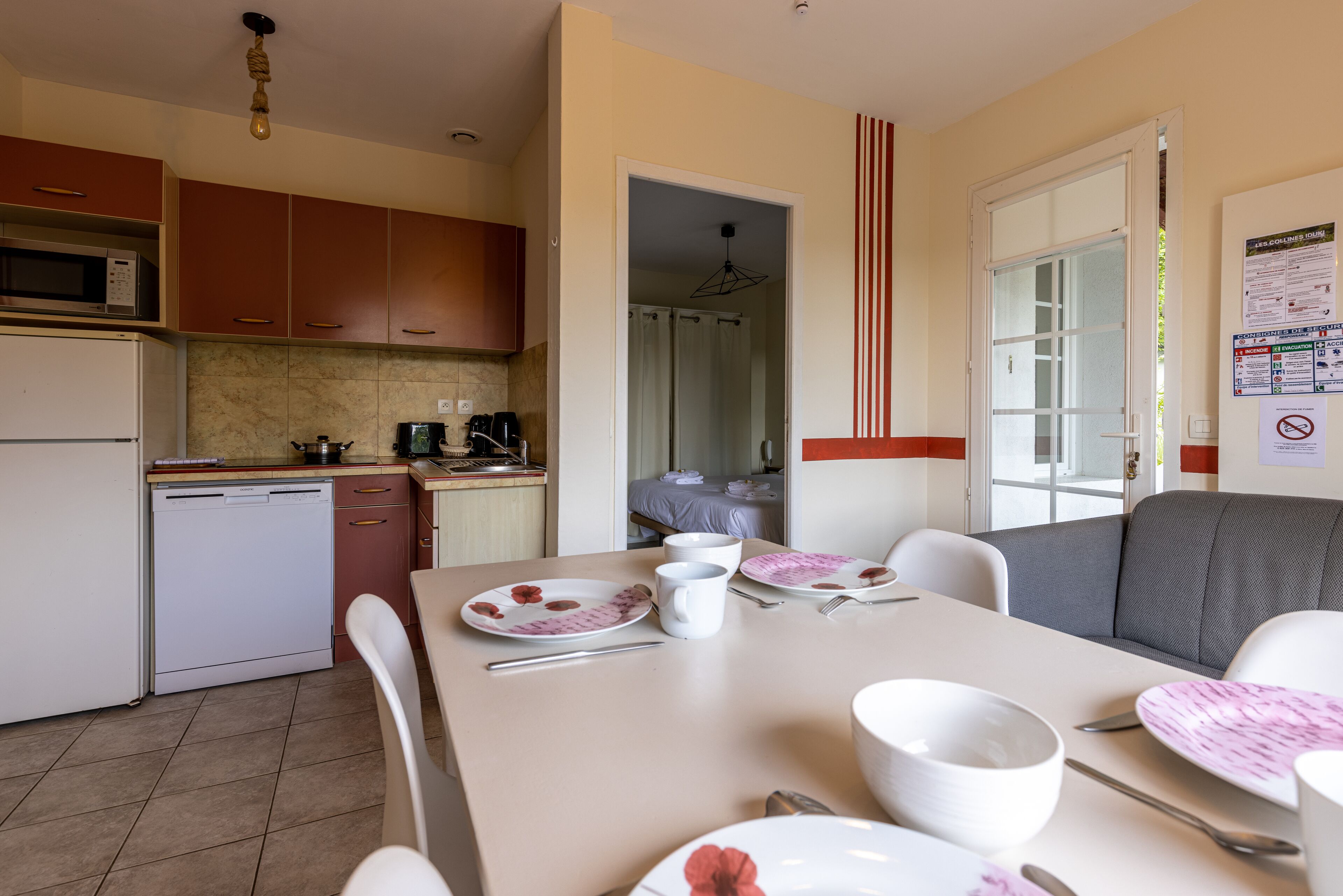 A modern kitchen with a dishwasher, microwave, and a dining area with a table set for two.
