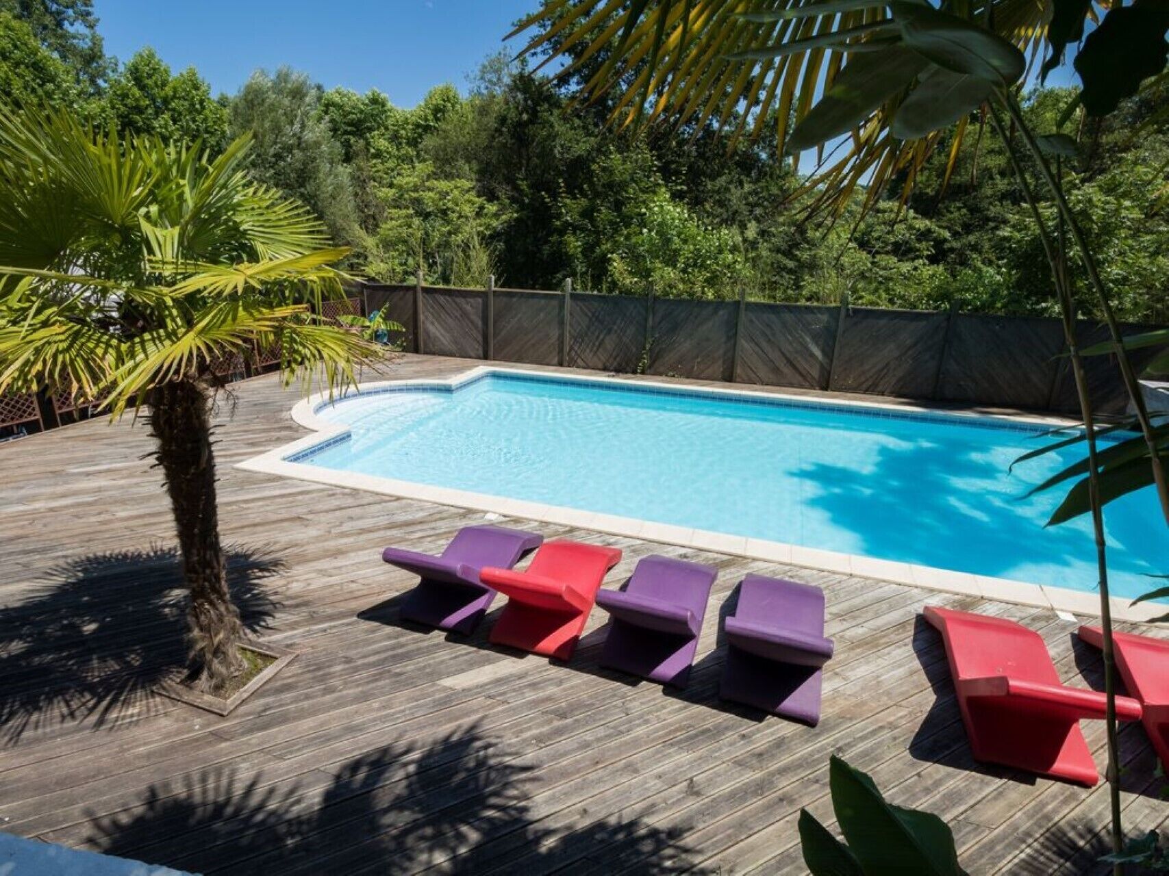 Una piscina con cubierta de madera y sillas de descanso.