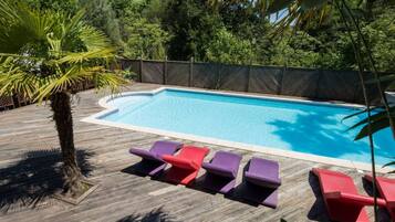 Una piscina con cubierta de madera y sillas de descanso.