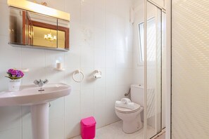 A bathroom with a white sink, mirror, toilet, and shower area. - Fidalsa Golf & Beach (Ciudad Quesada)
