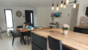 A modern kitchen with a wooden island, black chairs, and a dining table set for four. - Villa palm grove-private pool and bowling green (Saint-Jean-de-Monts)