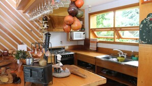 Une cuisine avec des meubles en bois, une cuisinière, un four à micro-ondes et une fenêtre donnant sur un paysage verdoyant.