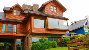 Une maison en bois avec de grandes fenêtres et une cheminée en pierre.