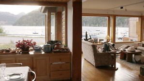 Une pièce avec une table en bois, un canapé et une vue sur des bateaux sur un lac.