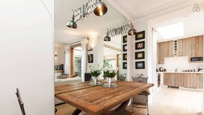 A dining area with a wooden table, metal chairs, and pendant lighting. - Retreat to a Stylish Flat in Chelsea (London)