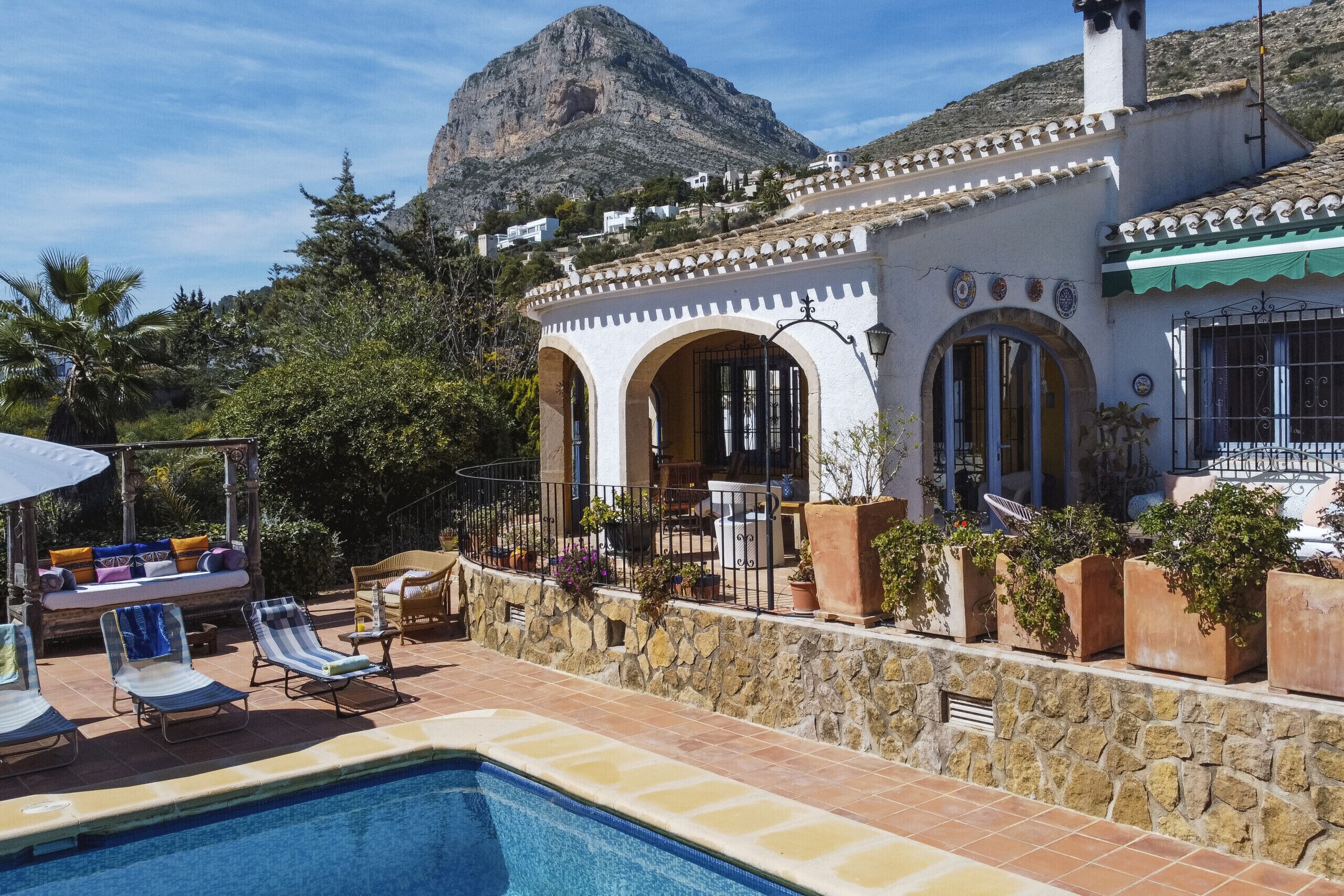 Uma área de piscina com espreguiçadeiras e um muro de pedra.