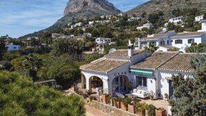 A hillside village with white buildings, a prominent mountain in the background, and lush greenery. - La Golondrina (Javea / Xàbia)
