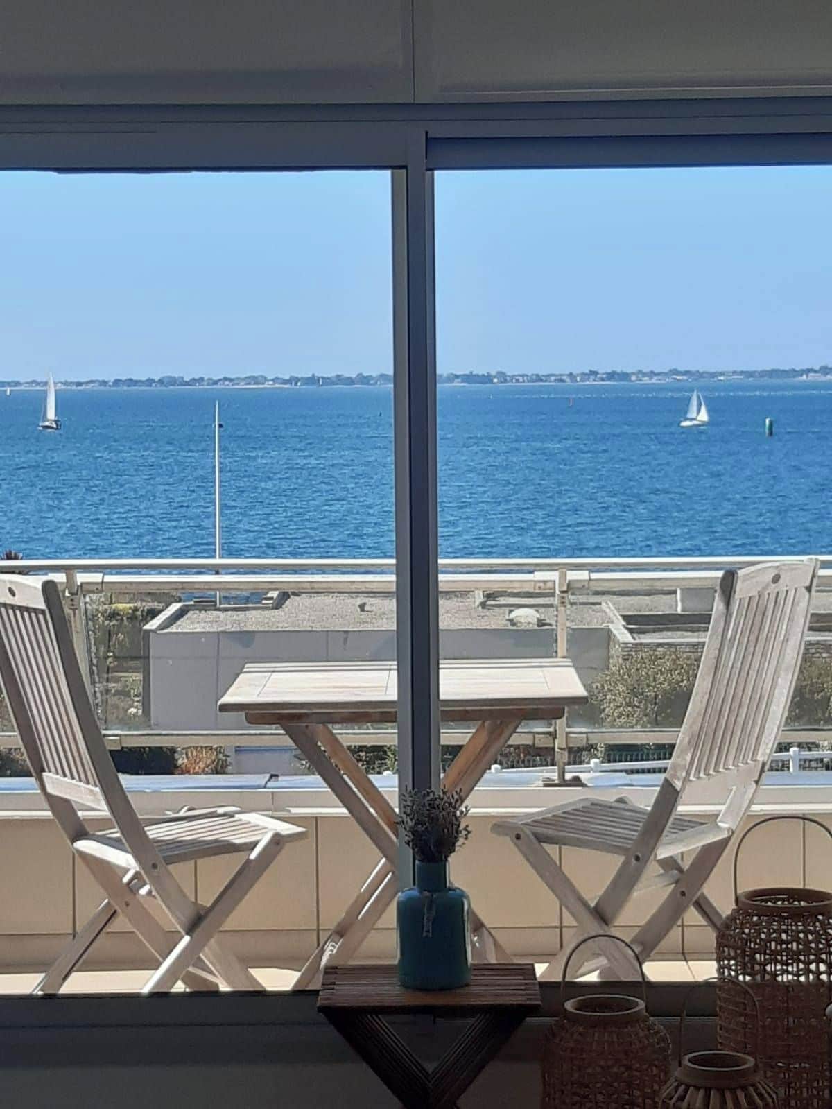 A balcony with a view of the sea, featuring two chairs and a table.