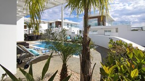 A modern outdoor pool area with lounge chairs, palm trees, and a clear view of the sky. - SUNDAY - 3bed Villa walking distance to Ayia Napa Center (Ayia Napa)