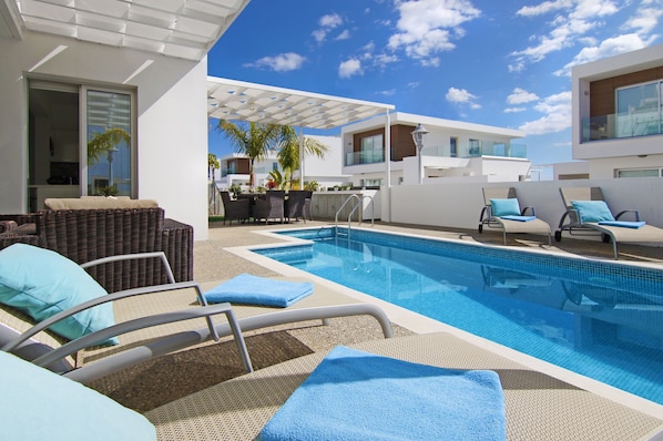 A swimming pool area with lounge chairs and a covered seating area.