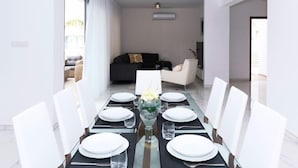 A modern dining area with a glass table set for six, surrounded by white chairs. - SUNDAY - 3bed Villa walking distance to Ayia Napa Center (Ayia Napa)