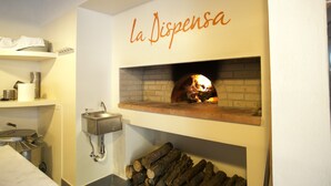 A kitchen with a wood-fired oven, a sink, and a shelf with plates. - B&B La Dispensa (Lamporecchio)