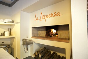 A kitchen with a wood-fired oven, a sink, and a shelf with plates.