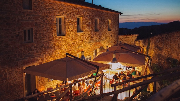 A stone building with outdoor seating and umbrellas. - B&B La Dispensa (Lamporecchio)