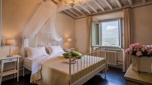 A bedroom with a four-poster bed, a chandelier, a view of the sea through a window, and a radiator. - B&B La Dispensa (Lamporecchio)