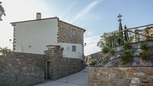 A stone building with a white upper section and a lower stone section, featuring a small balcony and a door. - B&B La Dispensa (Lamporecchio)