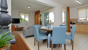 A modern living room with a dining area, a sofa, a TV, and a kitchen in the background. - MADISON - 3Bed Villa with private pool within walking distance to Pernera Resort Center (Paralimni)
