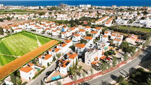 A residential area with white houses, orange roofs, and a large green field. - MADISON - 3Bed Villa with private pool within walking distance to Pernera Resort Center (Paralimni)
