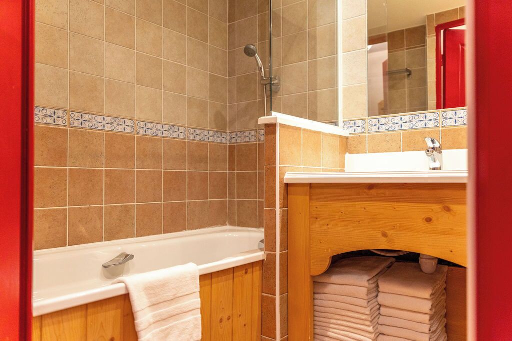 Un baño con bañera, tocador de madera y zona de ducha con azulejos.