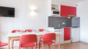 Uma cozinha compacta com micro-ondas, fogão e armários vermelhos.