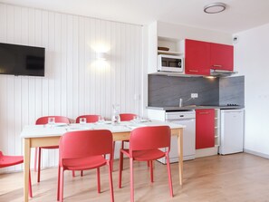 Une cuisine de taille réduite, équipée d’un four à micro-ondes, d’une cuisinière et de placards rouges.