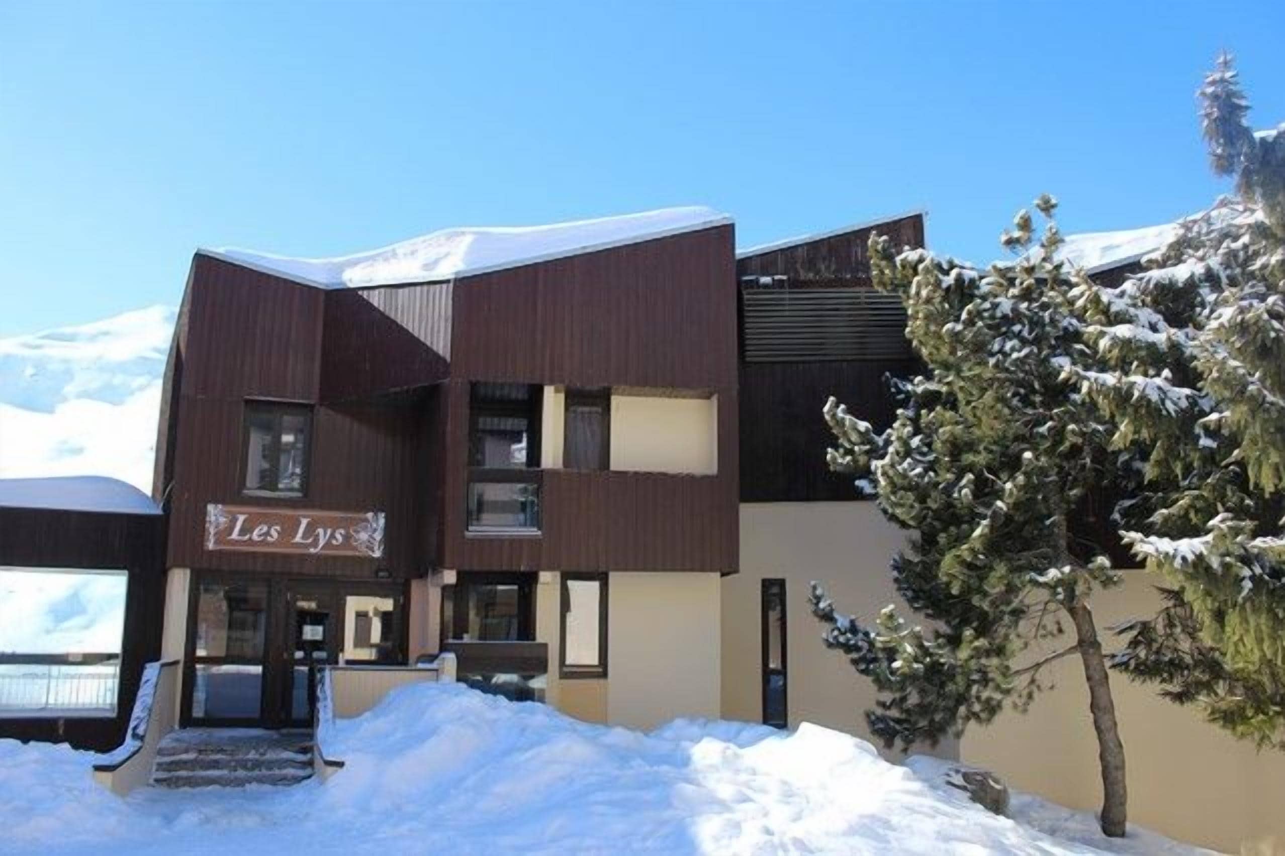 Un edificio con un letrero que dice 'Les Lys' y un paisaje cubierto de nieve.