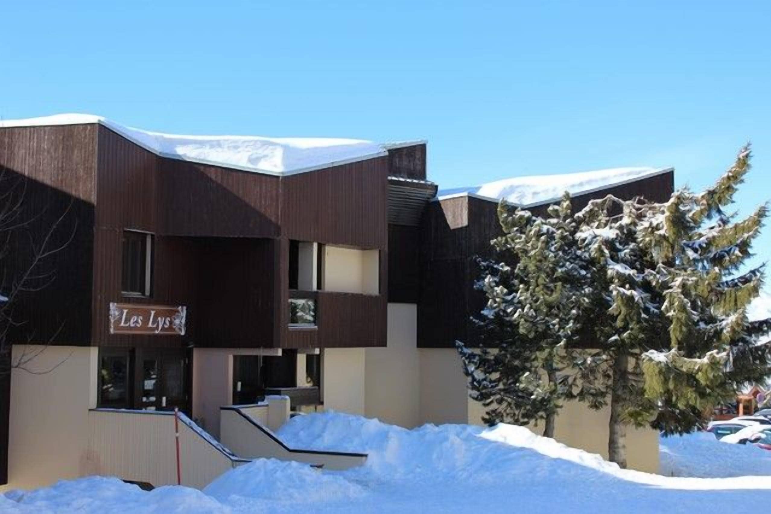 A building with a sign reading 'Les Lys' in front of a snow-covered landscape.