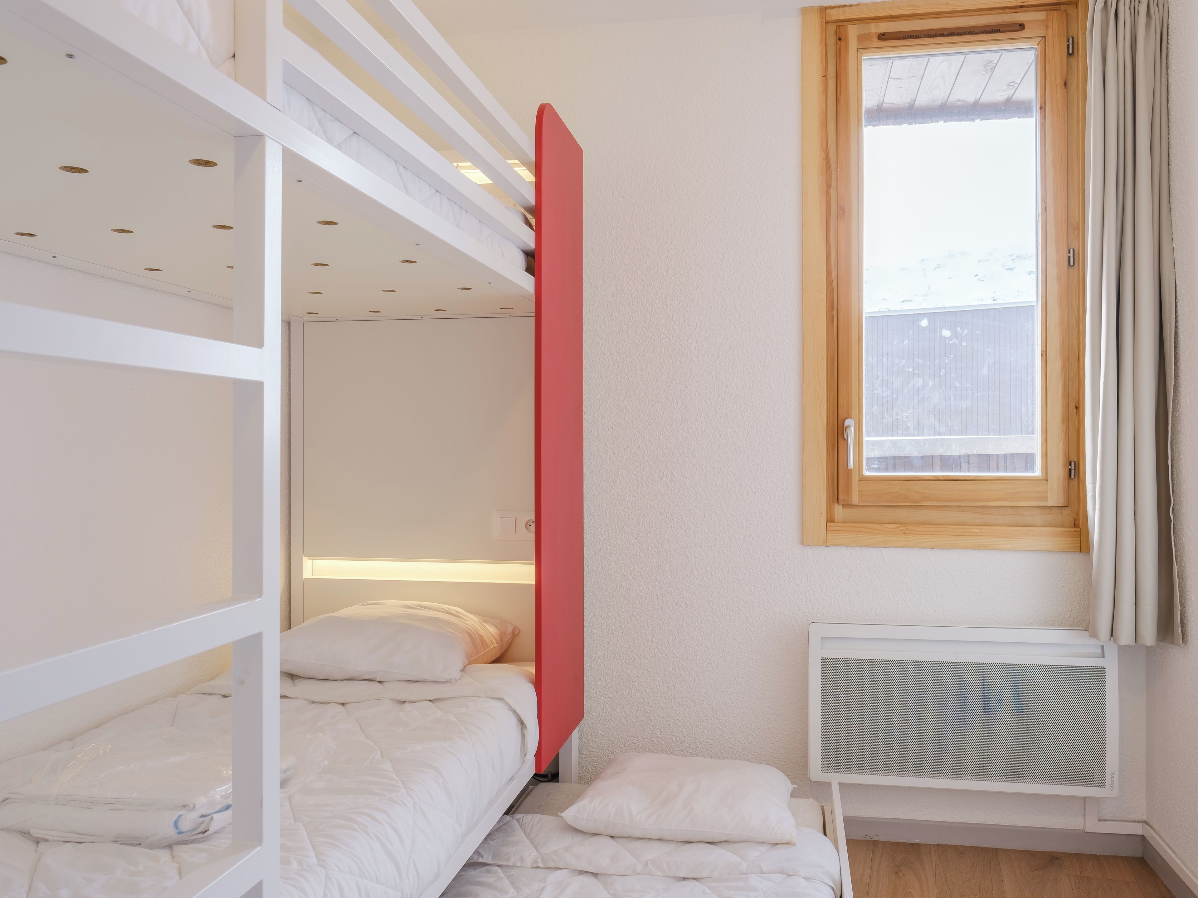 Ein Schlafzimmer mit Etagenbetten, einem Fenster und einer Heizung.