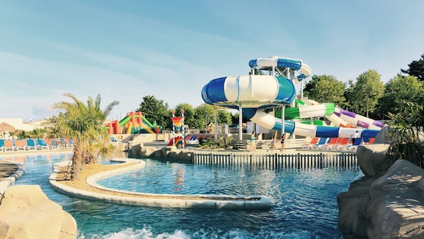 A water park with a large water slide, a pool, and palm trees. - Camping Club Sunissim Le Trianon (Les Sables-d'Olonne)