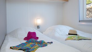 A hotel room with two beds, a wall-mounted light, and a window with a view. - Camping Sunissim Le Domaine Les Mûriers (Vendres)