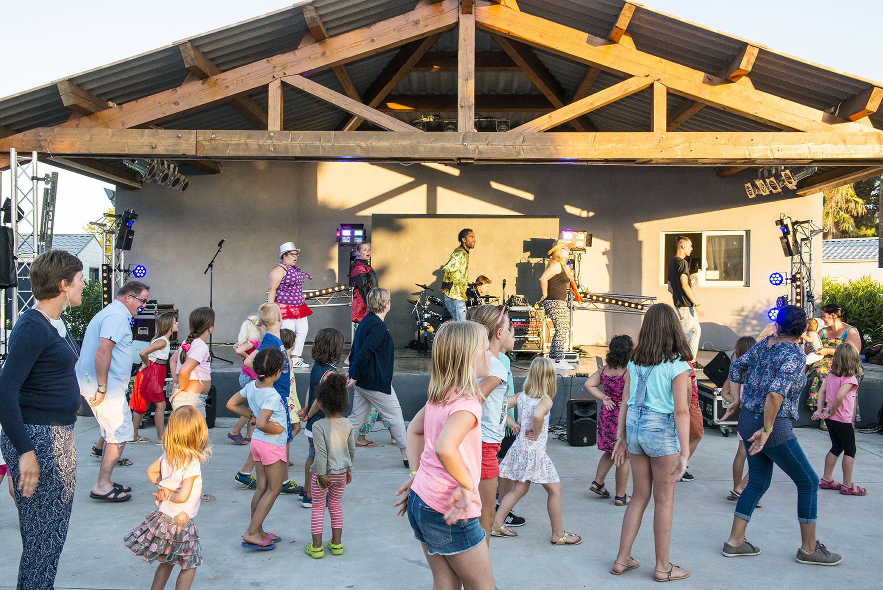 A stage with a band performing, surrounded by an audience of children and adults.