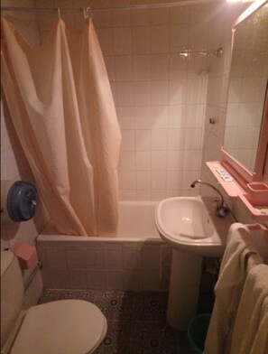 Une petite salle de bain avec une baignoire, un lavabo et des toilettes.
