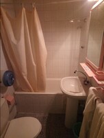 Ein kleines Badezimmer mit Badewanne, Waschbecken und Toilette.