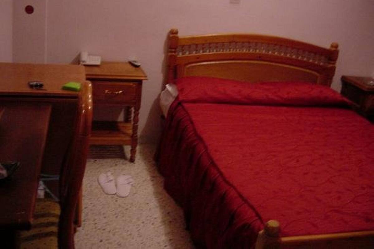 A bedroom with a wooden bed, a desk, and a chair.