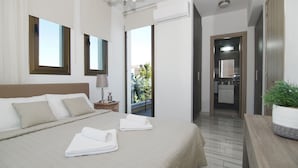 Una habitació d'hotel amb un llit, una tauleta de nit, una planta en testos i vistes cap a l'exterior.