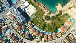 Vista aérea de uma área residencial costeira com casas, uma praia e um grande complexo de edifícios.