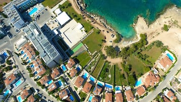 Vista aérea de una zona residencial costera con casas, una playa y un complejo de edificios grande.