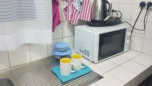 Eine Küche mit Mikrowelle, Wasserkocher und zwei Tassen auf einem Tablett.
