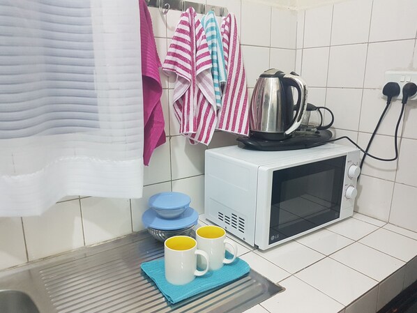Une cuisine équipée d’un four à micro-ondes, d’une bouilloire et de deux tasses sur un plateau.