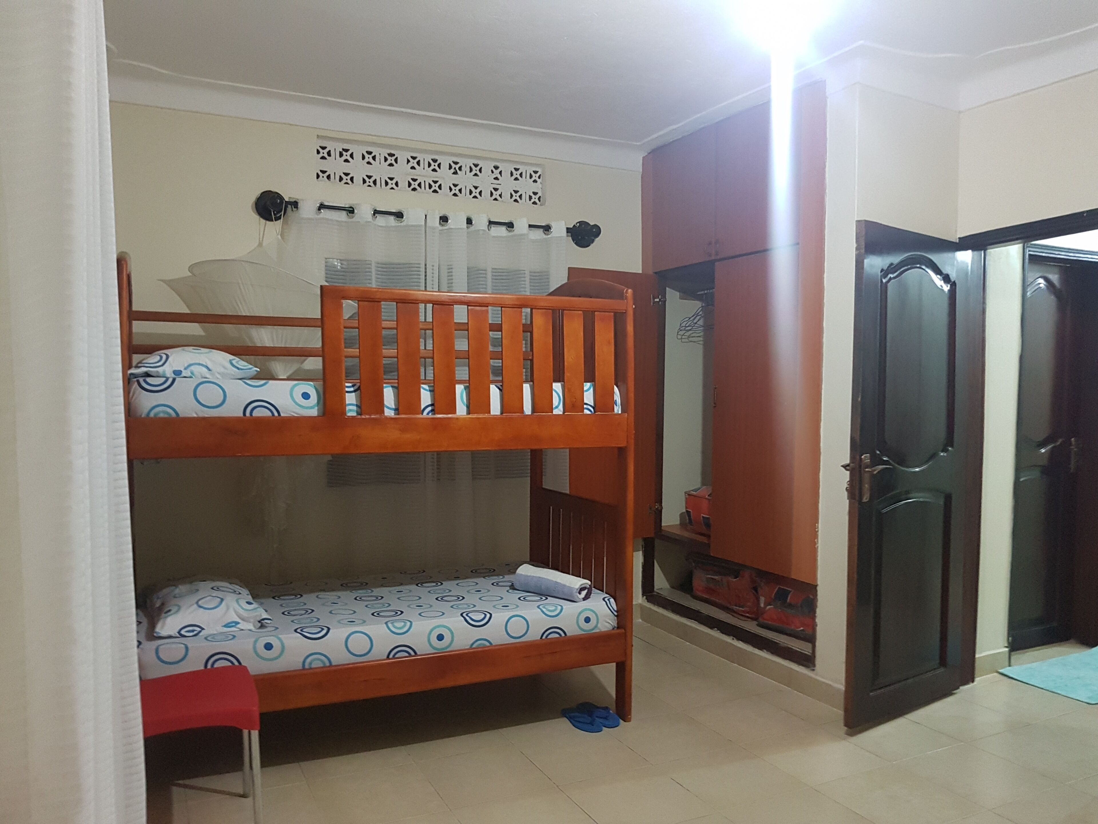 A room with a bunk bed, a wardrobe, and a door.