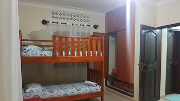 A room with a bunk bed, a wardrobe, and a door.