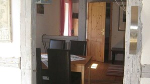 A rustic dining area with a wooden table and chairs, a hanging lantern, and a wooden door leading to another room. - Vacation under thatch (Postfeld)