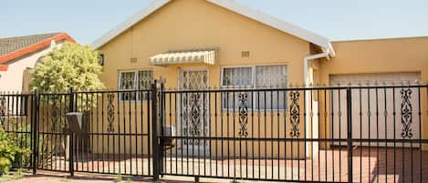 A building with a beige exterior, a black metal gate, and a brick pathway.