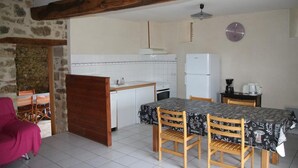 Cocina compacta con armarios blancos, un refrigerador y una mesa de comedor con sillas.