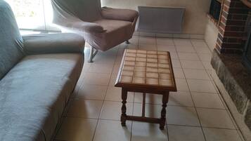 Ein Wohnzimmer mit einer Couch, einem Sessel, einem Holztisch, einem Fernseher und einem Kamin.