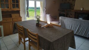 Un comedor con una mesa, sillas, un armario de madera, un televisor y una chimenea.
